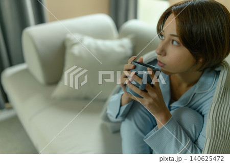 ソファで温かい飲み物を飲む女性 ソファで温かい飲み物を飲む女性 140625472