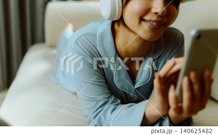 ヘッドホンをしてスマホを見る女性 ヘッドホンをしてスマホを見る女性 140625482