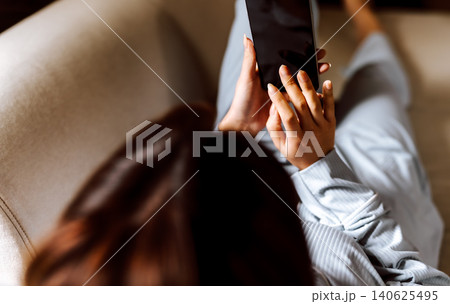 ソファでスマートフォンを操作する女性 ソファでスマートフォンを操作する女性 140625495