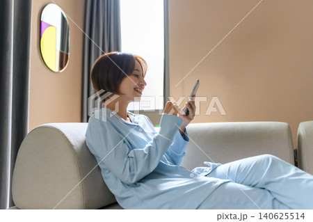 ソファでスマホを操作する笑顔の女性 ソファでスマホを操作する笑顔の女性 140625514