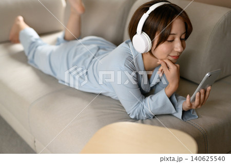 ソファでくつろぎスマホを見る若い女性 ソファでくつろぎスマホを見る若い女性 140625540
