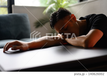 机で休息する日本人男性 机で休息する日本人男性 140626002