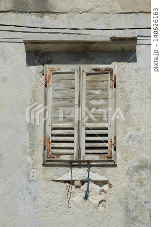 Old weathered wooden window shutters on a rustic stone wall 140626163