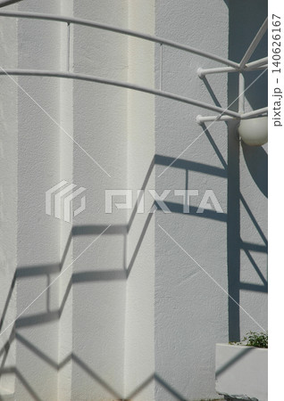 Geometric shadows of a metal railing on a white textured wall 140626167