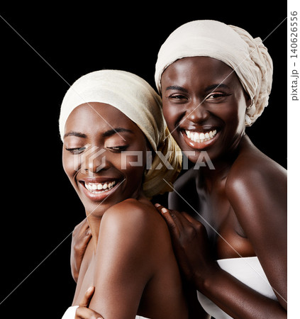 Black women, head wrap and beauty portrait with smile, skincare and cosmetics in studio with bonding. Girl friends, happy and African scarf with wellness and skin glow with makeup and dark background Black women, head wrap and beauty portrait with smile, skincare and cosmetics in studio with bonding. Girl friends, happy and African scarf with wellness and skin glow with makeup and dark background 140626556