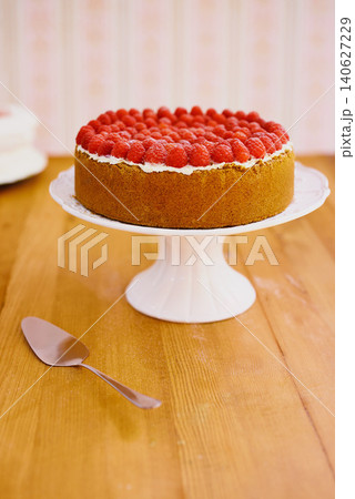 Stand, spoon and cheesecake with cream and raspberries on table for sweet snack for tea time at home. Bakery, catering and gourmet dessert with crust, frosting and fresh organic fruit in dining room. Stand, spoon and cheesecake with cream and raspberries on table for sweet snack for tea time at home. Bakery, catering and gourmet dessert with crust, frosting and fresh organic fruit in dining room. 140627229