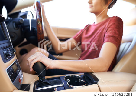 Closeup, gear and woman in luxury car and driving with steering wheel and travel with transportation. Driver, hands and person with expensive vehicle or road trip with destination and interior design Closeup, gear and woman in luxury car and driving with steering wheel and travel with transportation. Driver, hands and person with expensive vehicle or road trip with destination and interior design 140627291