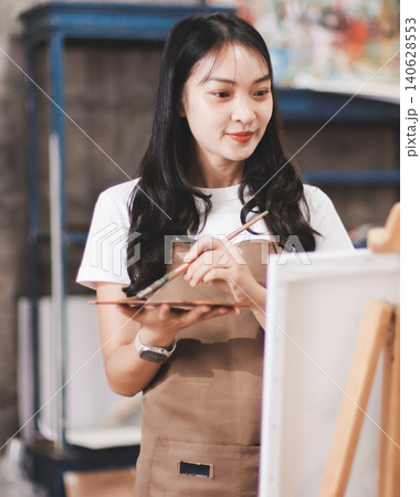 Female artist wears black hat posing near picture indoor the studio 140628553