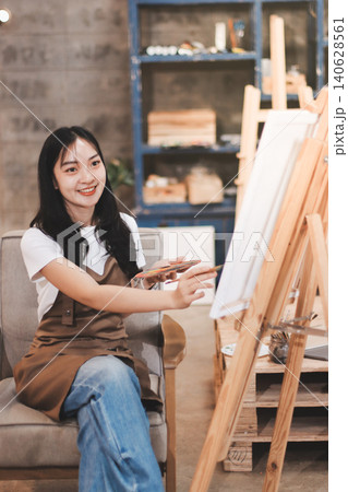 Female artist wears black hat posing near picture indoor the studio 140628561