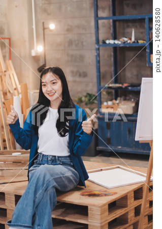 Female artist wears black hat posing near picture indoor the studio Female artist wears black hat posing near picture indoor the studio 140628580