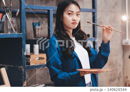 Female artist wears black hat posing near picture indoor the studio Female artist wears black hat posing near picture indoor the studio 140628584