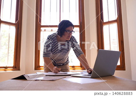 Businesswoman, laptop and notes at desk, office and technology for startup business owner. Entrepreneur, research and computer for female designer, writing and notebook for project in workplace 140628883