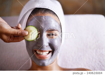 Woman, smile and facial in spa for skincare, clay mask and cosmetic treatment for break or peace. Young person with cucumber on eye and product for peel for natural or holistic therapy for wellness Woman, smile and facial in spa for skincare, clay mask and cosmetic treatment for break or peace. Young person with cucumber on eye and product for peel for natural or holistic therapy for wellness 140628884