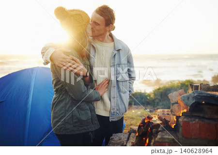 Happy couple, love and bonding together by campfire, blanket and romantic getaway with camping in forest. Man, woman and relax on vacation on weekend break, countryside and travel in woods for sunset 140628964