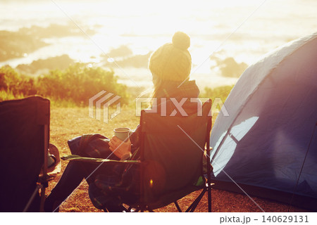 Sunset, camping and woman by tent on vacation, adventure or holiday in nature for travel. Evening, coffee and back of female person relaxing and drinking cappuccino in chair outdoor for weekend trip. 140629131