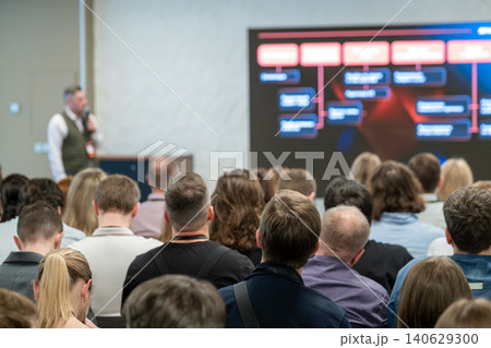 Business conference presentation with audience listening to speaker and large screen showing flowchart 140629300