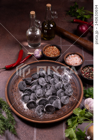 Black pelmeni dumplings with spices and cooking ingredients Black pelmeni dumplings with spices and cooking ingredients 140630694