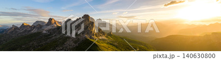 Dramatic sunset panorama of Ra Gusela at Passo Giau in the Italian Dolomites. Rugged limestone cliffs, golden sun rays and breathtaking alpine scenery under colorful clouds. 140630800