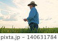 Modern agriculture worker, Farmer inspecting cereal plants, Wheat farming in summer, Outdoor work in agriculture, Farming and food production, Agricultural professional at field, Farming clothes and 140631784