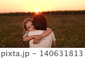 Mother and daughter hug at sunset, Family love in the evening sun, Warm embrace in nature, Parenting moments outdoors, Child comforted by parent, Emotional sunset bonding, Tender moments in a field 140631813