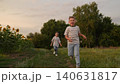 Happy children running in a summer field, Smiling boy and girl playing outdoors, Kids enjoying nature and fresh air, Siblings having fun together at sunset, Carefree childhood moments in the 140631817