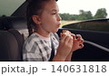 little girl child eating burger in car, happy person, Travel meal solutions for kids, Simple pleasures of eating on the go, Family bonding over fast food, Joyful eating during car rides, Little foodie 140631818