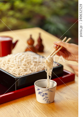 木製テーブルで箸を使ってそば麺を食べる日本の食事シーン 木製テーブルで箸を使ってそば麺を食べる日本の食事シーン 140632529