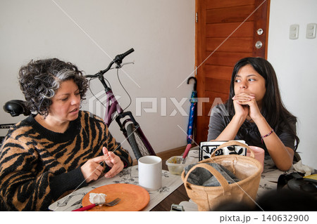Mother and daughter are sitting at a table, one of them is wearing a striped shirt Mother and daughter are sitting at a table, one of them is wearing a striped shirt 140632900