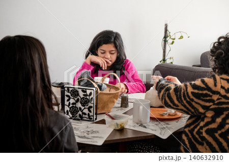 A girl in a pink shirt sits at a table with a basket and a book 140632910