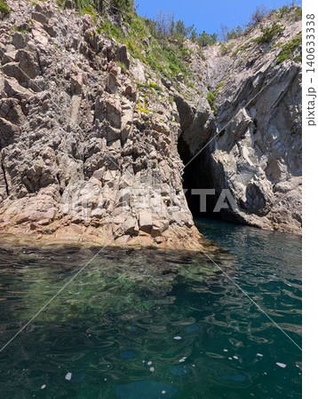 断崖絶壁の岩肌とエメラルドグリーンの海に広がる神秘的な洞窟 140633338