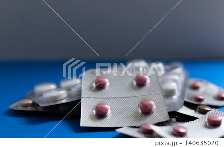 Medical drugs and pills in silver shiny package isolated on blue background Medical drugs and pills in silver shiny package isolated on blue background 140635020