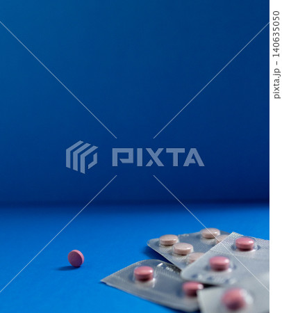 Silver blister packs of medicines and a single pill on a blue background.Health care industry Silver blister packs of medicines and a single pill on a blue background.Health care industry 140635050