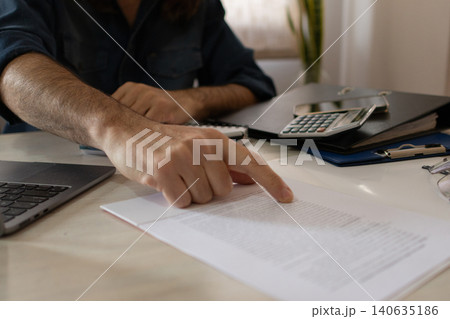 Close-up of the hands of an agent at his workplace explaining the contract to his client. 140635186