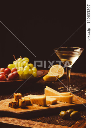 A dry gin martini, premium spirits, fresh grapes, hints of lemon, and a gourmet cheese board with various appetizers, creating a refined culinary experience. A dry gin martini, premium spirits, fresh grapes, hints of lemon, and a gourmet cheese board with various appetizers, creating a refined culinary experience. 140635207