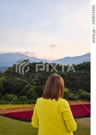 Woman yellow jacket admiring colorful flower fields forest mountain layers at sunset creating peaceful travel nature lifestyle scene Woman yellow jacket admiring colorful flower fields forest mountain layers at sunset creating peaceful travel nature lifestyle scene 140635682