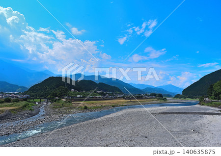 快晴の青空と雄大な山並みに包まれた清流の流れる広大な河原風景 140635875