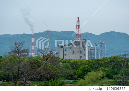 山並みを背景にした工業地帯の工場と煙突の煙 山並みを背景にした工業地帯の工場と煙突の煙 140636285