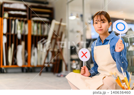 アトリエで正解の札を掲げる女性 140636460