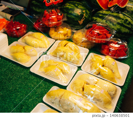 Fresh durian and sliced tropical fruits in plastic containers for sale at a Thai market 140638501