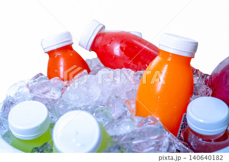 Organic cold pressed raw vegetable and fruit juice bottle in crushed ice bucket on white background. Healthy drink. Trendy juice beverage. Detox juice from fresh fruits and vegetables. Orange juice. Organic cold pressed raw vegetable and fruit juice bottle in crushed ice bucket on white background. Healthy drink. Trendy juice beverage. Detox juice from fresh fruits and vegetables. Orange juice. 140640182