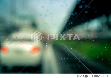 Rain drops on windshield. Car driving on asphalt road on rainy day. Windshield window of car with raindrops on glass windscreen. Traffic jam on rainy season. Bad weather in stormy day. Travel by car. Rain drops on windshield. Car driving on asphalt road on rainy day. Windshield window of car with raindrops on glass windscreen. Traffic jam on rainy season. Bad weather in stormy day. Travel by car. 140640203