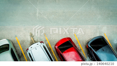Top view of car parked at concrete car parking lot with yellow line of traffic sign on the street. Above view of car in a row at parking space. No available parking slot. Outside car parking area. Top view of car parked at concrete car parking lot with yellow line of traffic sign on the street. Above view of car in a row at parking space. No available parking slot. Outside car parking area. 140640210