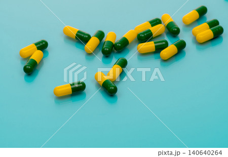 Green-yellow capsules spread on blue background. Tramadol capsule pills for relieve severe cancer pain. Painkiller medicine. Opioids drug. Pharmaceutical product for pain treatment. Prescription drug. Green-yellow capsules spread on blue background. Tramadol capsule pills for relieve severe cancer pain. Painkiller medicine. Opioids drug. Pharmaceutical product for pain treatment. Prescription drug. 140640264