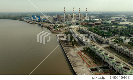Aerial drone view of large industrial power plant and energy facility beside river waterfront, electricity generation infrastructure with smokestacks cooling systems and heavy industrial production. Aerial drone view of large industrial power plant and energy facility beside river waterfront, electricity generation infrastructure with smokestacks cooling systems and heavy industrial production. 140640468