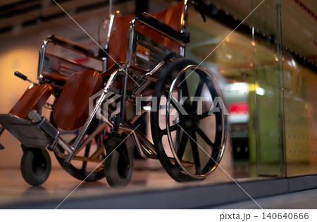 Blurred empty wheelchair near lift in private hospital for service patient and disabled people. Medical equipment in hospital for assistance handicapped people. Chair with wheels for patient care. Blurred empty wheelchair near lift in private hospital for service patient and disabled people. Medical equipment in hospital for assistance handicapped people. Chair with wheels for patient care. 140640666