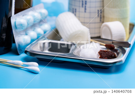 Wound care dressing set and stainless steel plate on blue background. Cotton ball and cotton stick with povidone-iodine for wounds, burns and cuts. Wound care supplies. Medical equipment for nurse. 140640708