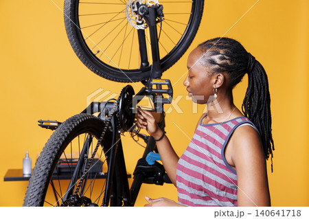 Athletic woman carefully adjusts and repairs bicycle components with a multitool, with female gripping specialized equipment for adjusting and tightening bicycle hub and axle. Athletic woman carefully adjusts and repairs bicycle components with a multitool, with female gripping specialized equipment for adjusting and tightening bicycle hub and axle. 140641718