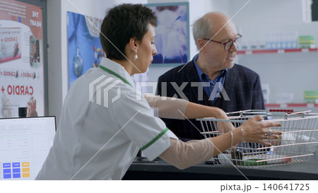 Healthcare professional at drugstore counter scanning pharmaceutical items from elderly client shopping basket, with senior man buying headache stopping medicaments in pharmacy. Healthcare professional at drugstore counter scanning pharmaceutical items from elderly client shopping basket, with senior man buying headache stopping medicaments in pharmacy. 140641725