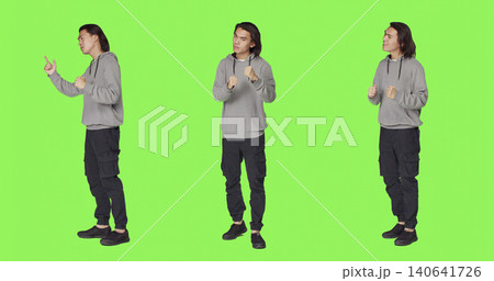 Young adult throwing punches in the air, being furious and aggressive on camera, with man starting fight with fists, being violent and mad, dangerous behavior on full body green screen. 140641726