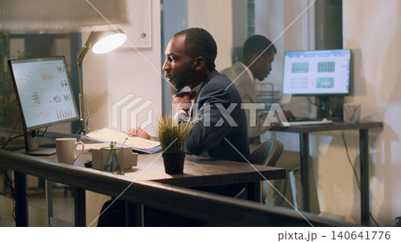 Manager checking online paperwork is in order during nightshift, with management executive looking over every office computer to verify employees managed to finish project tasks in time. Manager checking online paperwork is in order during nightshift, with management executive looking over every office computer to verify employees managed to finish project tasks in time. 140641776